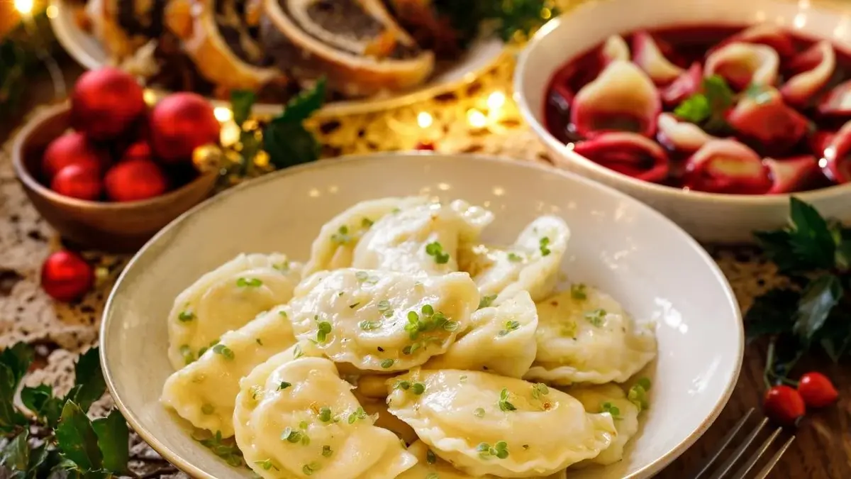 Pierogi wigilijne, w tle czerwony barszcz, makowiec i bombki.