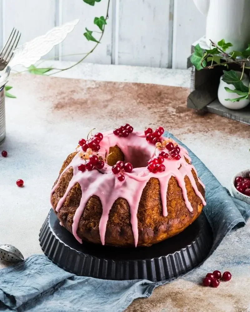 Świąteczna babka polana różowym lukrem i udekorowana porzeczkami