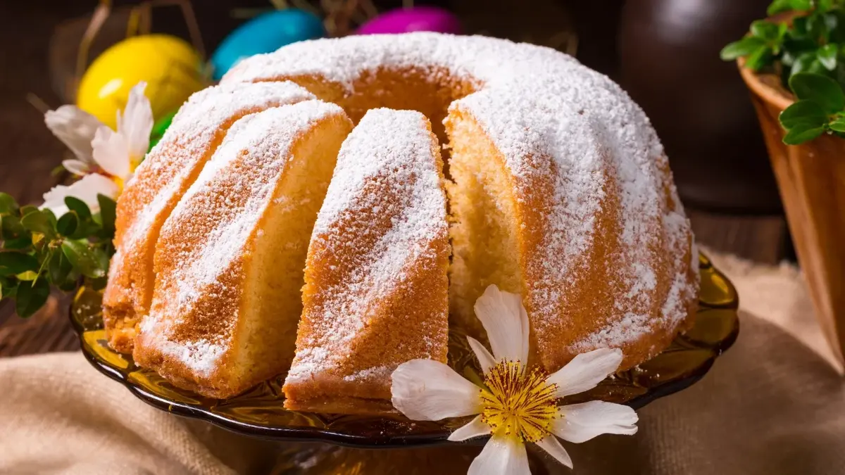 babka wielkanocna z kwiatkiem na tle kolorowych jajek i doniczki z rośliną