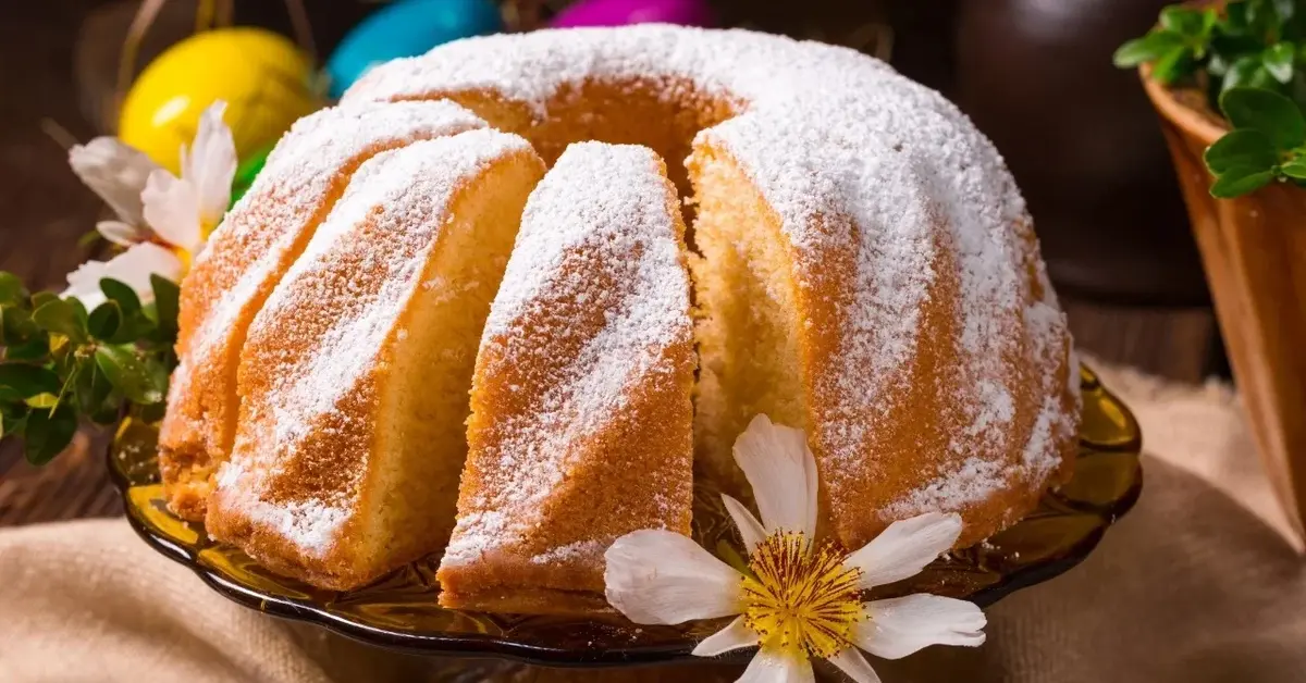 babka wielkanocna z kwiatkiem na tle kolorowych jajek i doniczki z rośliną