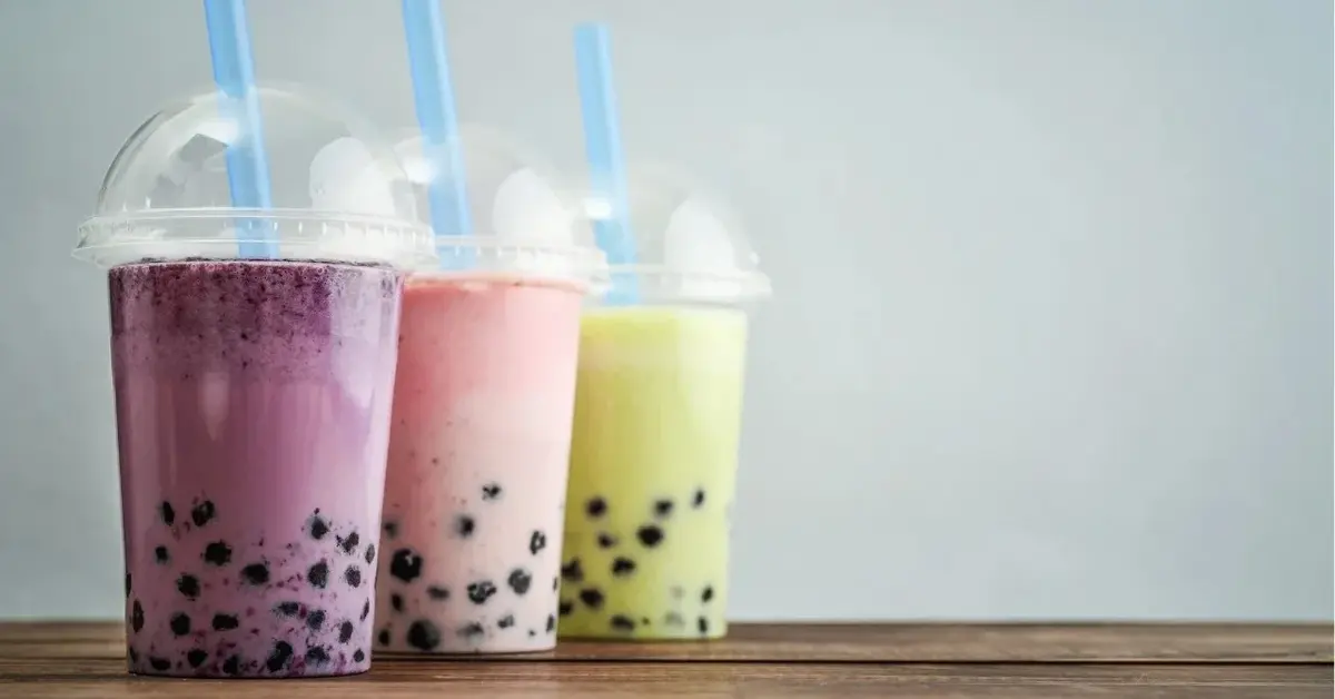 bubble tea napoje z tapiok fioletowy rowy i zielony w kubkach plastikowych z pokrywką i słomką