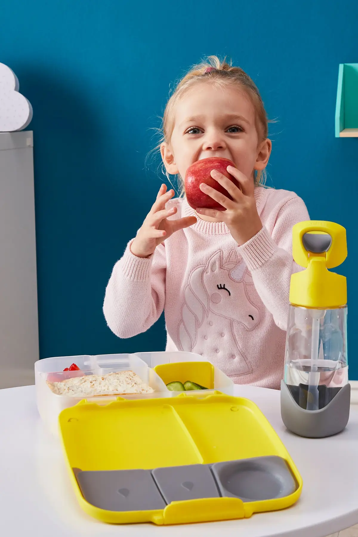 Mała dziewczynka jedząca drugie śniadanie z eleganckiego lunchboxa