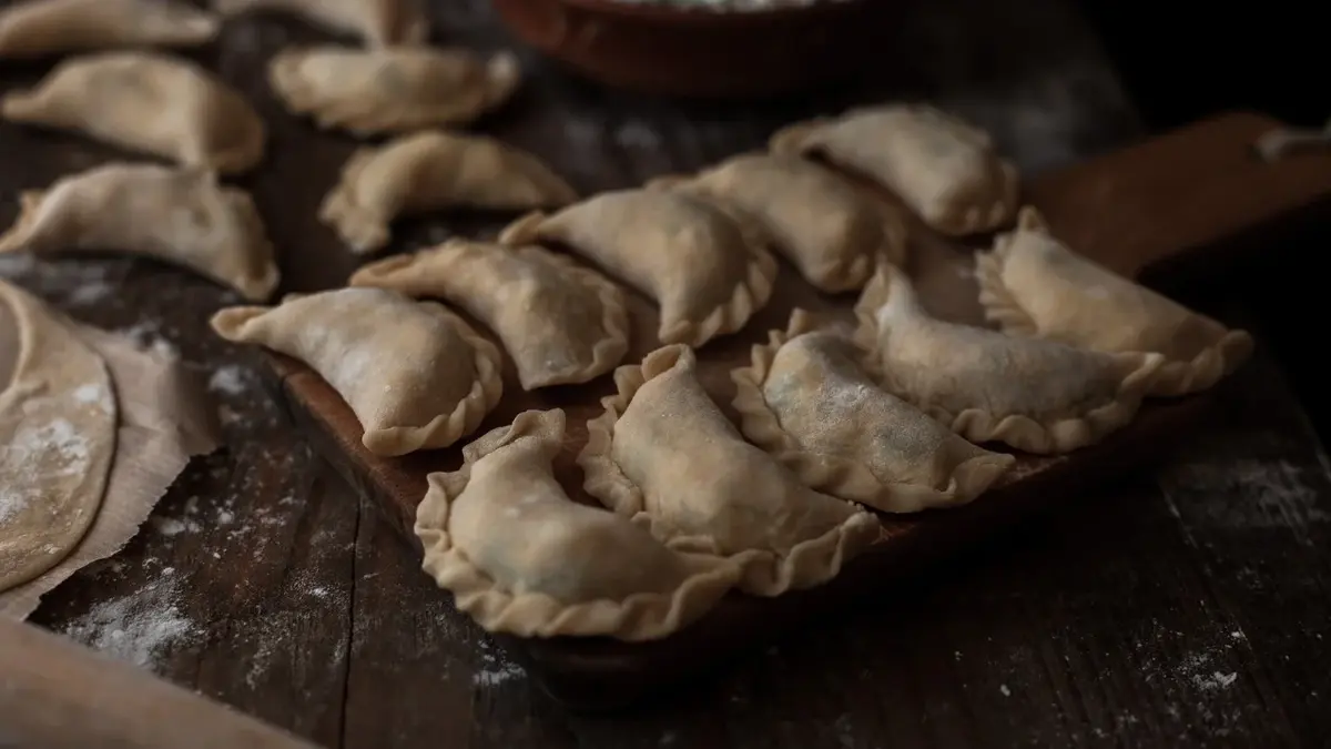 pierogi surowe równo ułożone na stolnicy