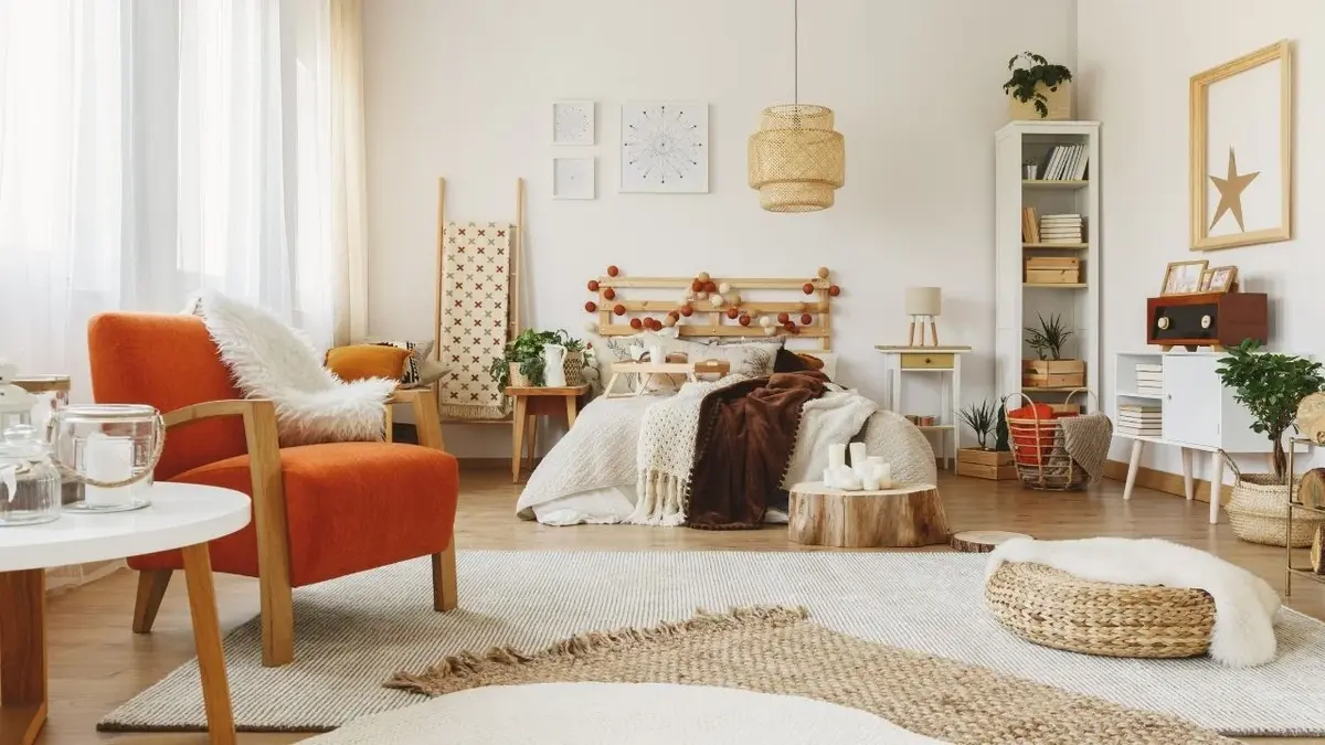 Sypialnia scandi boho z drewnianym łóżkiem i rudym fotelem