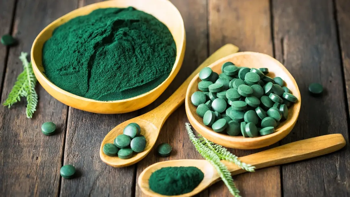 Spirulina w proszku i tabletkach na łyżeczkach i w miseczkach 