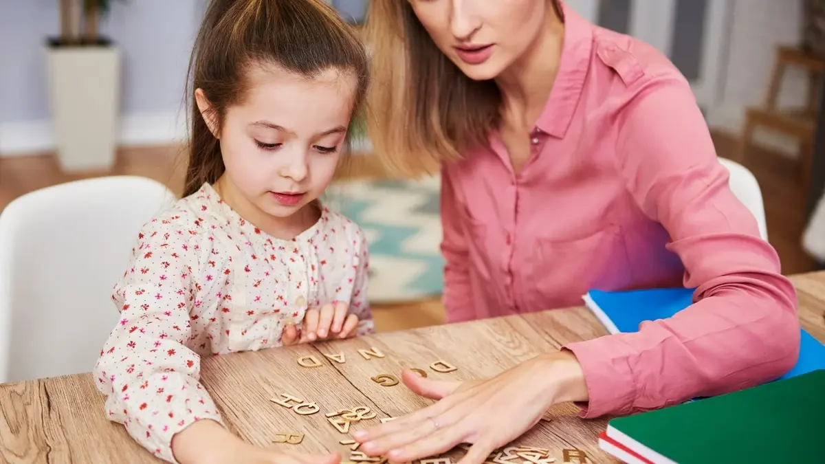 Mama i córka przy stole uczące sie literek