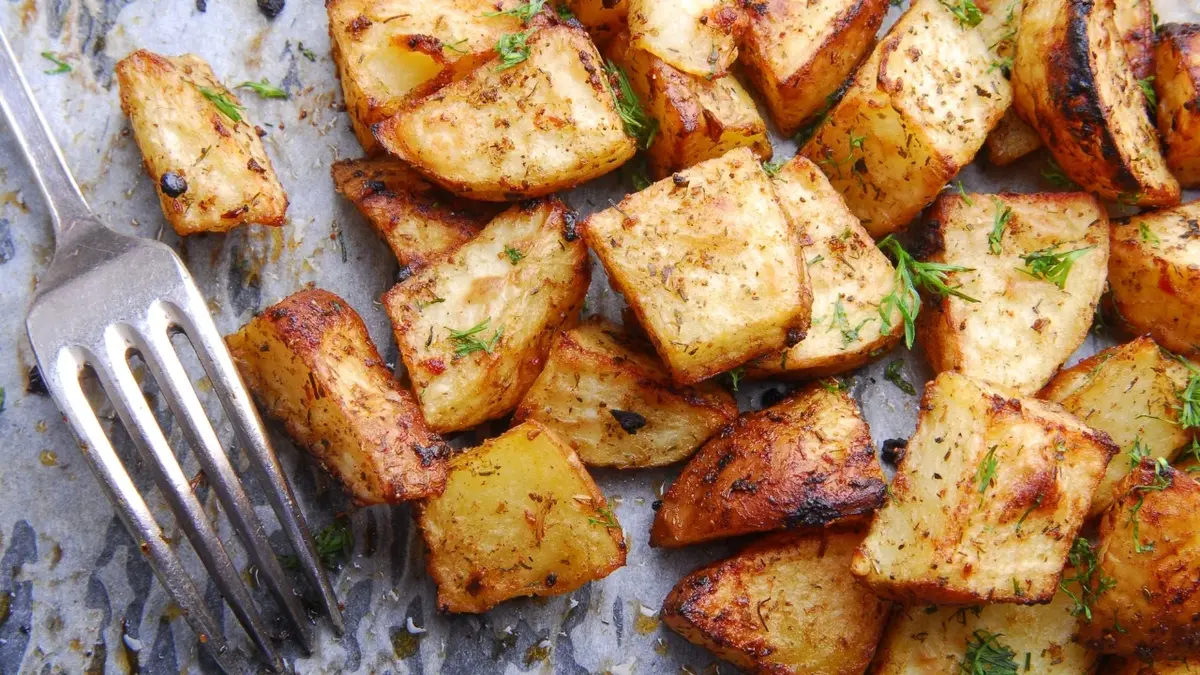 Ziemniaki pieczone pokrojone w kostkę. Obok widelec