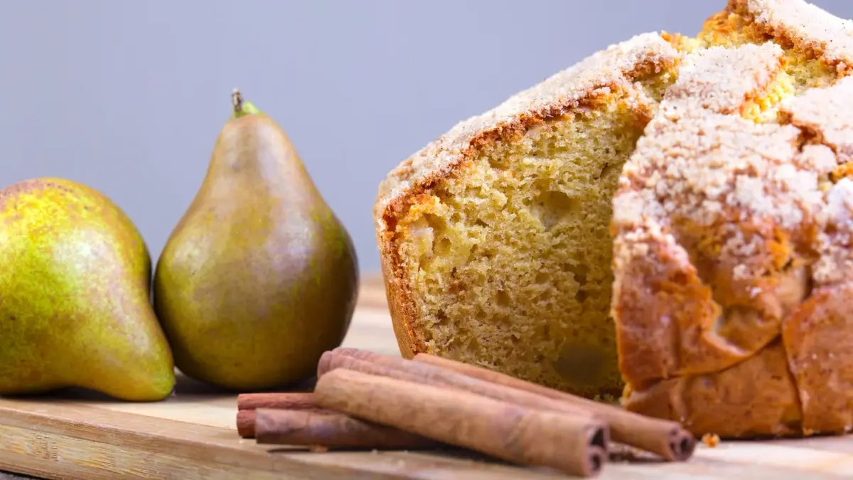 ciasto jesienne z gruszkami, obok dwie gruszki i laska cynamonu