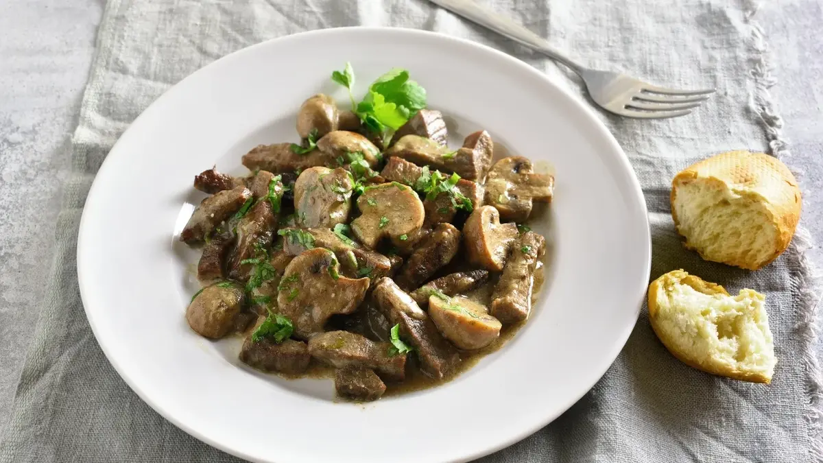 Stroganoff z pieczarkami w białym głębokim talerzu 