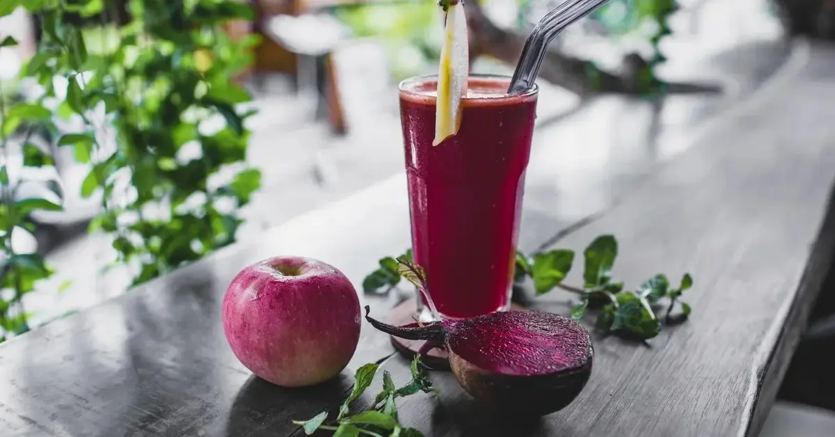 Smoothie z buraków i jabłek w szklance na drewnianym blacie.