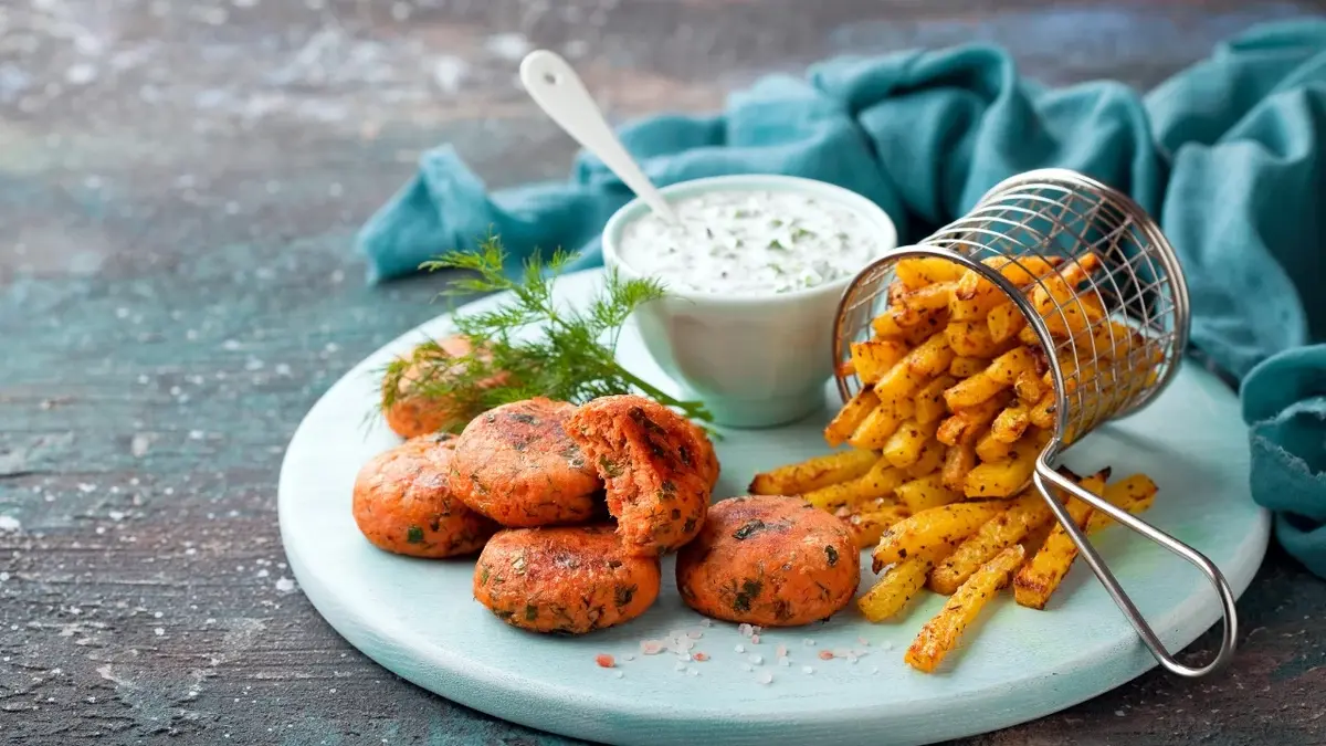 Frytki z kalarepy z wege kotlecikami i sosem na talerzu 