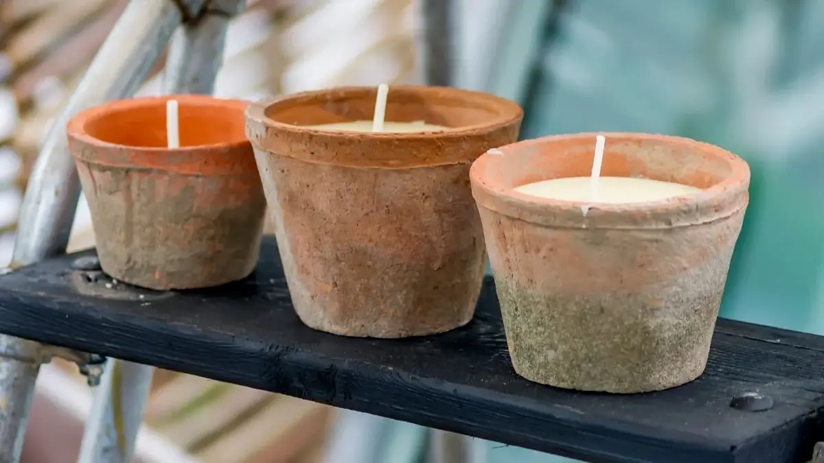 Domowe znicze w ceramicznych doniczkach, ustawione na półce